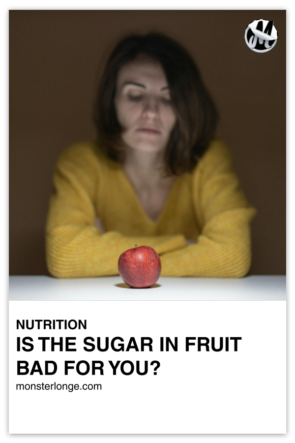 Is The Sugar In Fruit Bad For You? written in text with image of a woman looking at an apple on a table.